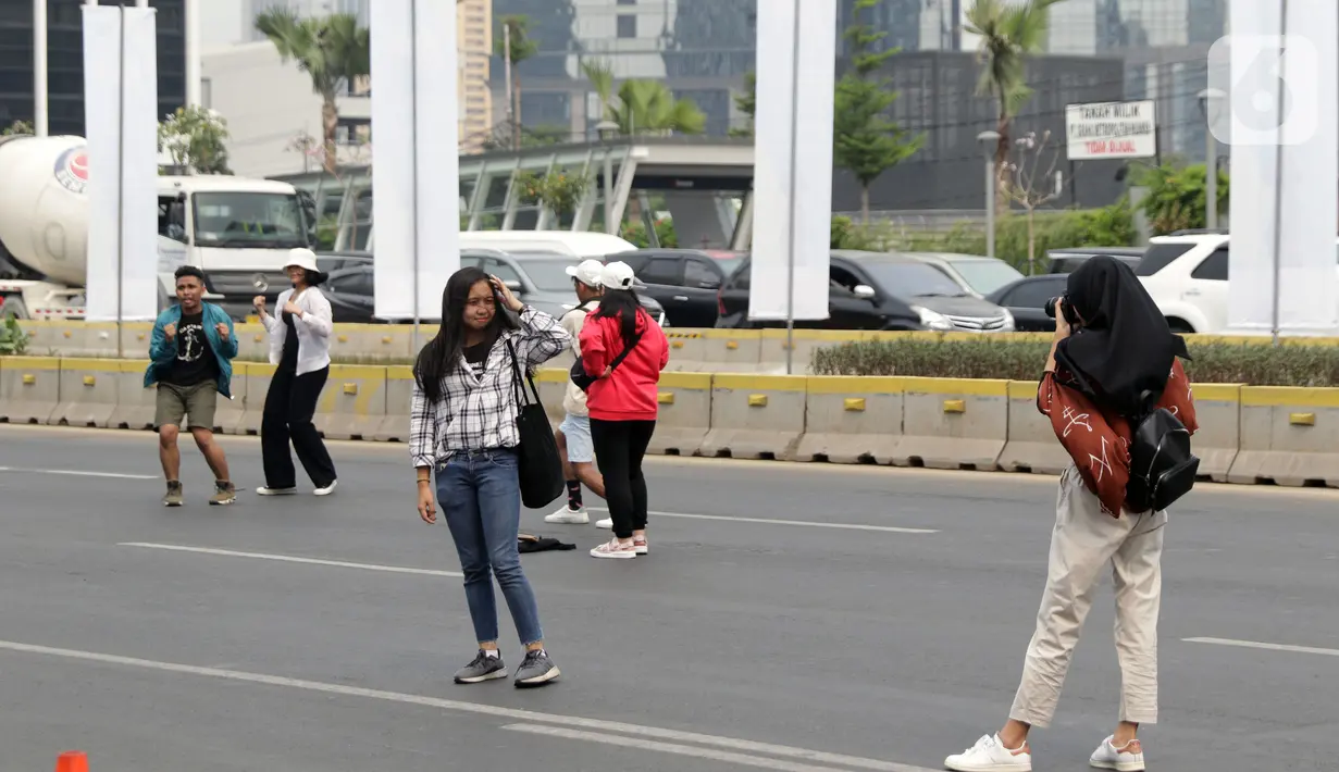 Warga memanfaatkan kondisi lengang sebagian ruas jalan Jenderal Sudirman untuk berfoto, Jakarta, Minggu (27/10/2019). Sebagian ruas Jalan Jenderal Sudirman dialihkan akibat  berlangsungnya Karnaval Kendaraan Listrik yang bertajuk Jakarta Langit Biru. (Liputan6.com/Helmi Fithriansyah)