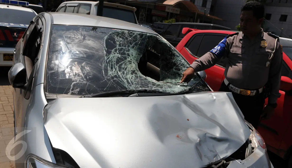 Petugas kepolisian menunjukkan mobil yang menabrak pejalan kaki di Jalan Boulevard Artha Gading, Jakarta, Sabtu (9/1/2016). Akibat kejadian tersebut, satu pengendara sepeda dan satu pejalan kaki meninggal di lokasi. (Liputan6.com/Helmi Afandi)
