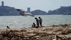 Warga setempat berjalan di pantai yang dipenuhi puing-puing setelah Badai Otis menerjang Acapulco, Meksiko, Kamis, 26 Oktober 2023. (AP Photo/Marco Ugarte)