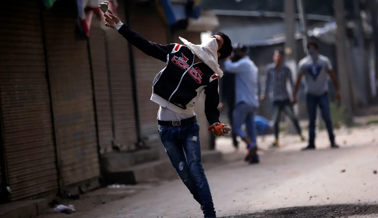 Demonstran melempar batu saat aksi di Srinagar, India, Selasa (13/9). Mereka protes karena pembunuhan yang terjadi di Kashmir belum lama ini. (REUTERS / Danish Ismail)