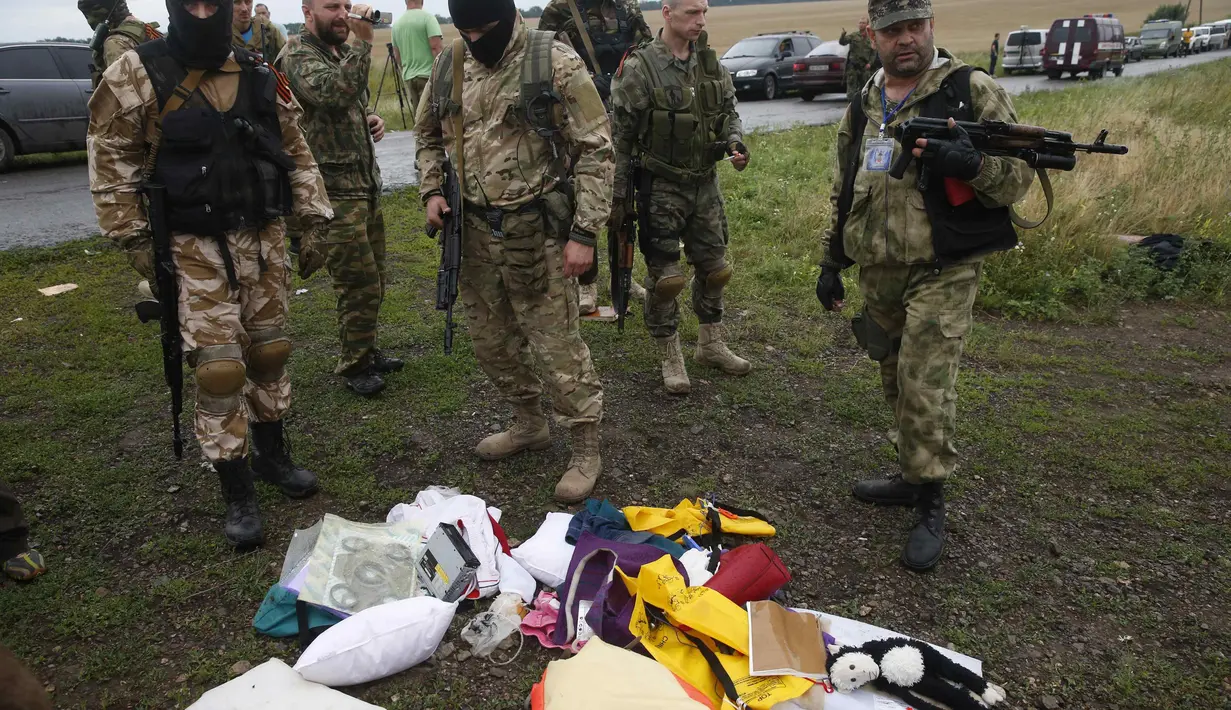 Separatis Pro-Rusia melihat barang-barang milik penumpang MH17 yang berserakan, UKraina, Jumat (18/7/14). (REUTERS/Maxim Zmeyev)