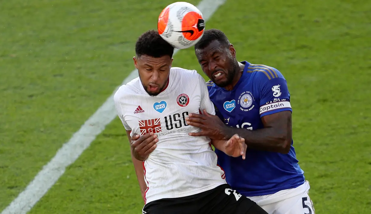 Penyerang Sheffield United, Lys Mousset melompat saat berebut bola dengan bek Leicester City, Wes Morgan dalam lanjutan Liga Inggris pekan ke-36 di Stadion King Power, Kamis (16/7/2020). Leicester City sukses menggulung tamunya, Sheffield United dengan skor 2-0. (David Davies/Pool via AP)