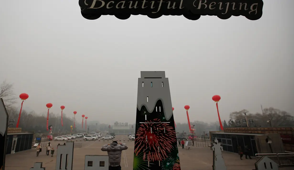 Kabut asap menyelimuti Lapangan Tiananmen, Beijing, Rabu (15/1/2015). Seorang pria berdiri di atas panggung saat berpose dekat menara observatorium di Beijing. (REUTERS/Kim Kyung-Hoon)