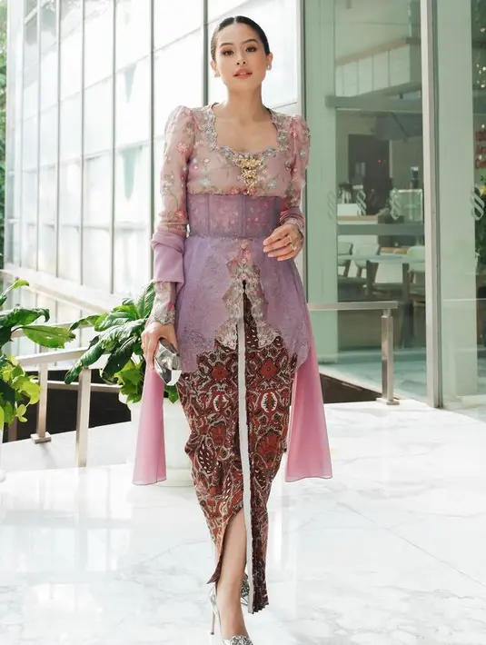 Maudy Ayunda tampil elegan mengenakan kebaya lengan puff warna pink dengan bordiran bunga. Dipadukan obi ungu panjang senada dengan selendang, dipadukan kain batik coklat sebagai bawahan. [@maudyayunda]