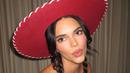 Kendall Jenner memamerkan perutnya yang kencang dalam balutan kemeja putih bergaya kartun dengan kerah besar, kancing, dan detail manset kuning. (Instagram/Kendalljenner)