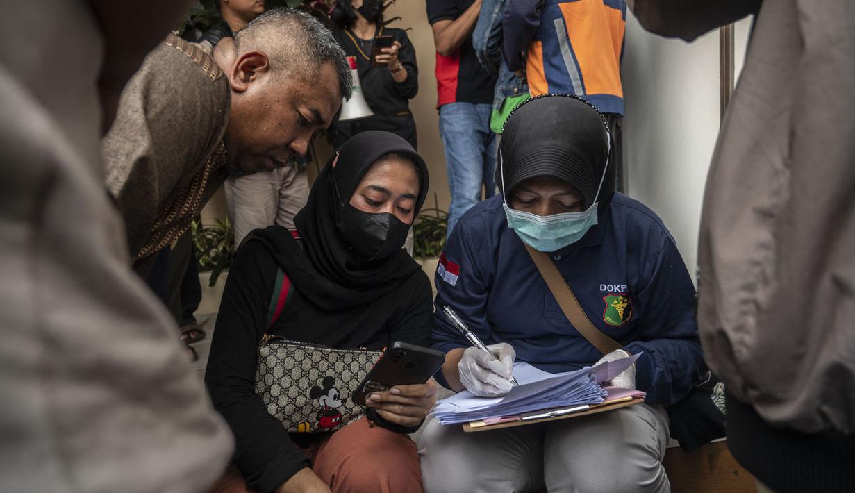 Polisi mengidentifikasi kerabat korban saat mereka mengantri jenazah di Malang, Jawa Timur pada 2 Oktober 2022. Sedikitnya 174 orang tewas di stadion sepak bola Indonesia ketika ribuan penggemar tuan rumah yang marah menyerbu lapangan dan polisi menanggapi dengan gas air mata yang memicu desak-desakan, kata pihak berwenang pada 2 Oktober. (AFP/Juni Kriswanto)