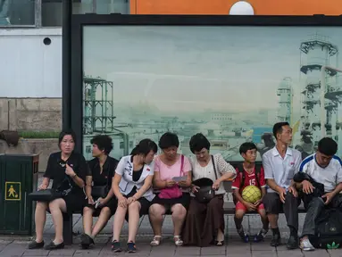 Foto yang diambil pada 28 Juli 2017 memperlihatkan sejumlah calon penumpang menunggu bus di sebuah halte di Pyongyang, Korea Utara. (Ed JONES/AFP)