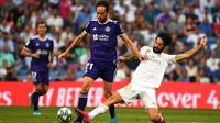 Gelandang Real Madrid, Isco, menekel gelandang Valladolid, Michel, pada laga La Liga di Stadion Santiago Bernabeu, Madrid, Sabtu (24/8). Kedua klub bermain imbang 1-1. (AFP/Gabriel Bouys)