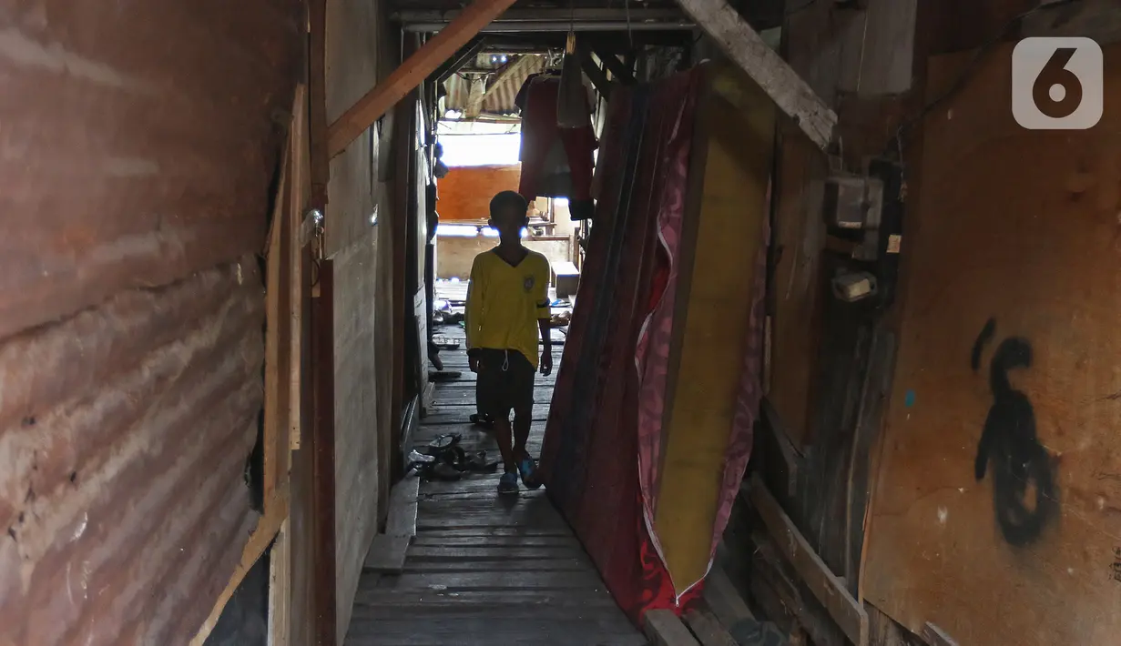Seorang anak melintas di antara rumah di Kampung Apung, Jakarta, Selasa (26/11/2019). Untuk mengurangi genangan air di Kampung Apung, Pemprov DKI berencana membuat saluran air pada 2020 mendatang, selain itu akan disediakan beberapa pompa mobile saat musim hujan tiba. (Liputan6.com/Herman Zakharia)