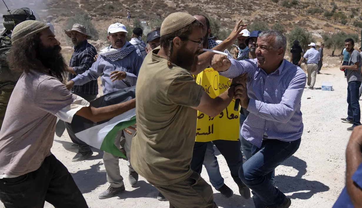 Pengunjuk rasa Palestina meninju pemukim Israel saat bentrokan antara kedua belah pihak sementara aktivis Palestina memblokir jalan yang melewati Desa Mughayer, Tepi Barat, utara Ramallah, 29 Juli 2022. Warga Palestina yang memprotes aktivitas permukiman Israel memblokir jalan utama dan bentrok dengan pemukim Israel, sementara tentara menembakkan gas air mata untuk membubarkan mereka. (AP Photo/Nasser Nasser)