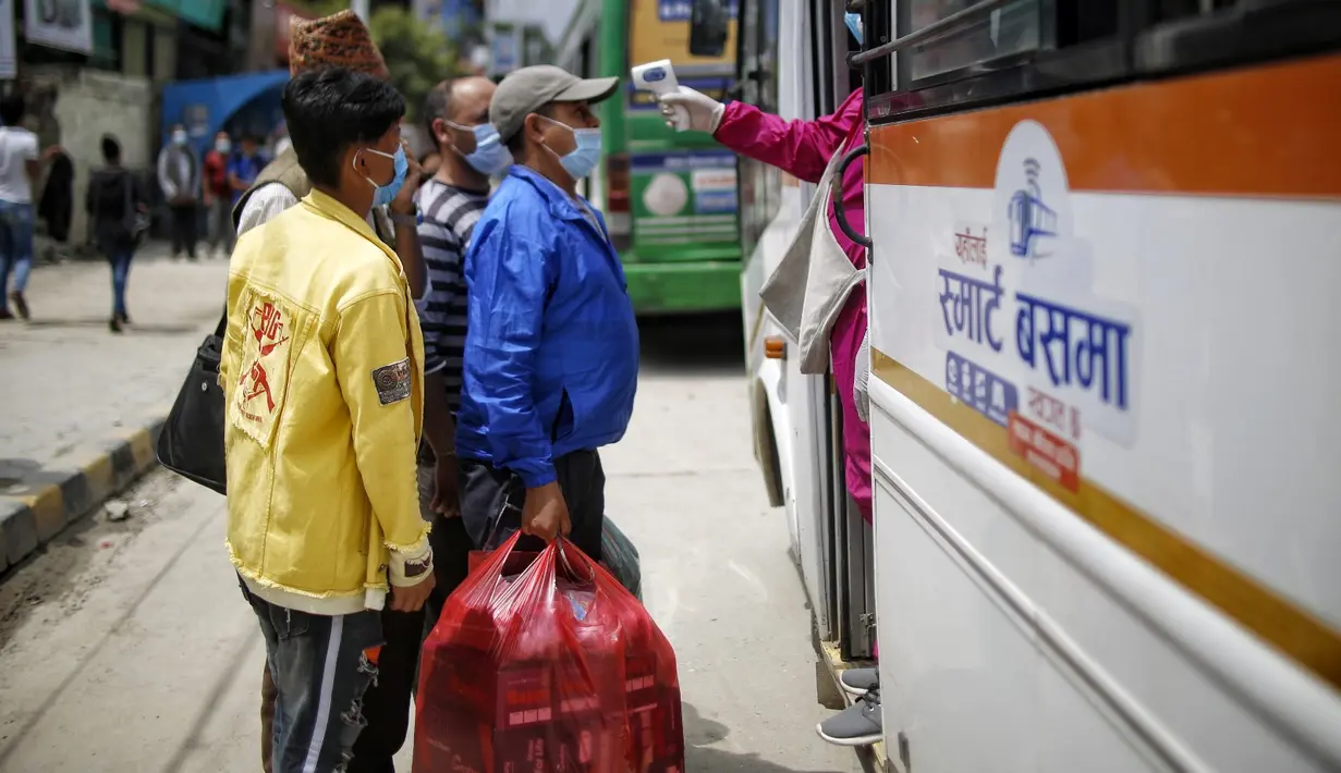 Seorang staf mengukur suhu tubuh penumpang bus di Kathmandu (16/7/2020). Beberapa perusahaan angkutan umum di Lembah Kathmandu mulai mengoperasikan kembali rute mereka untuk pertama kalinya dalam hampir empat bulan setelah menerima persyaratan operasional dari pemerintah. (Xinhua/Sulav Shrestha)