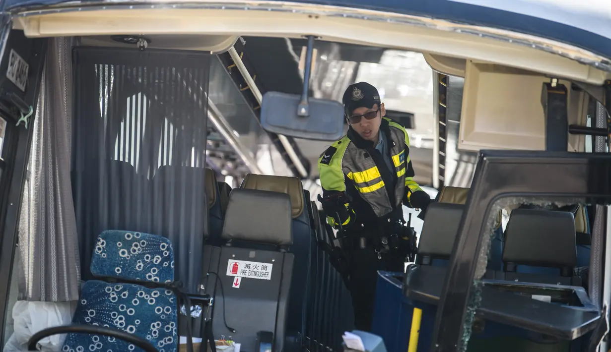 Polisi mengecek bus usai bertabrakan dengan taksi di Hong Kong (30/11). Bus tersebut dalam perjalanan ke bandara Hong Kong bertabrakan dengan taksi, kata polisi, dengan penumpang dilaporkan terlempar dari jendela bus. (AFP Photo/Anthony Wallace)