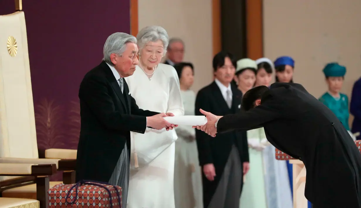 Kaisar Akihito menyerahkan teks pidato kepada bendahara agung usai menyampaikan berpidato dalam upacara turun takhta di Istana Kekaisaran, Tokyo, Jepang, Jumat (30/4/2019). Kaisar Akihito resmi turun takhta setelah tiga dekade memimpin. (Japan Pool via AP)