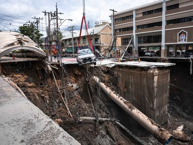 Sebuah kendaraan dievakuasi dari tepian lubang jalan yang amblas di dekat sebuah rumah sakit di Bangkok, Thailand pada Rabu 24 September 2025. (Chanakarn Laosarakham/AFP)