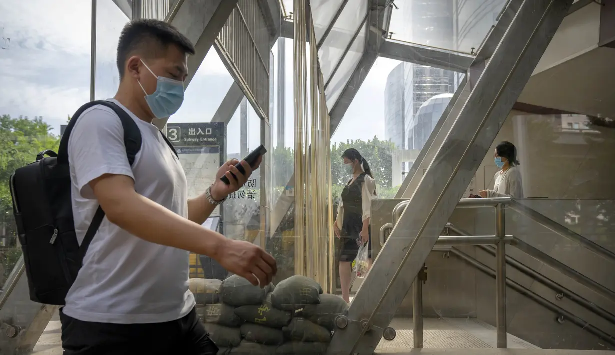 Komuter yang mengenakan masker berjalan keluar dari stasiun kereta bawah tanah yang baru dibuka kembali di kawasan pusat bisnis di Beijing, China, Selasa (31/5/2022). Penguncian COVID-19 di Shanghai telah mencekik ekonomi nasional dan sebagian besar mengurung jutaan orang di rumah mereka. (AP Photo/Mark Schiefelbein)