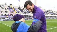 Foto pada tanggal 25 Februari 2018, seorang anak laki-laki memberi ban kapten kepada pemain Fiorentina, Davide Astori sebelum pertandingan Liga Italia di Florence. Davide Astori meninggal pada usia 31 tahun. (AFP Photo/Claudio Giovannini)