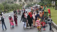 Warga bersama anak-anak berjalan-jalan di kawasan Monumen Nasional, Jakarta, Jumat (19/4). Libur panjang perayaan Paskah 2019 dimanfaatkan warga untuk berwisata di kawasan Monumen Nasional. (Liputan6.com/Helmi Fithriansyah)