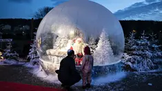 Seseorang yang berpakaian seperti Sinterklas terlihat dalam bola salju seukuran aslinya saat membuka musim Natal di Kebun Binatang Aalborg, di tengah krisis virus corona yang berlanjut, di Aalborg, Denmark pada Jumat (13/11/2020). (Henning Bagger / Ritzau Scanpix / AFP)