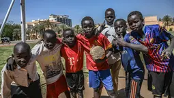 Sejumlah anak Sudan berpose sebelum bermain sepak bola di ibu kota Khartoum (23/4). Negara ini berbatasan dengan Mesir di utara, Laut Merah di timur laut, Kongo dan Afrika Tengah di barat daya, Chad di barat, dan Libya di barat laut. (AFP Photo/Ozan Kose)