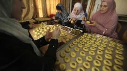 Perempuan Palestina membuat kue tradisional berisi kurma dan kacang-kacangan dalam persiapan untuk liburan Idul Fitri, di kota Hebron, Tepi Barat, pada 28 April 2022. Seluruh umat Muslim di dunia akan menandai berakhirnya bulan suci Ramadhan dengan Idul Fitri. (HAZEM BADER / AFP)