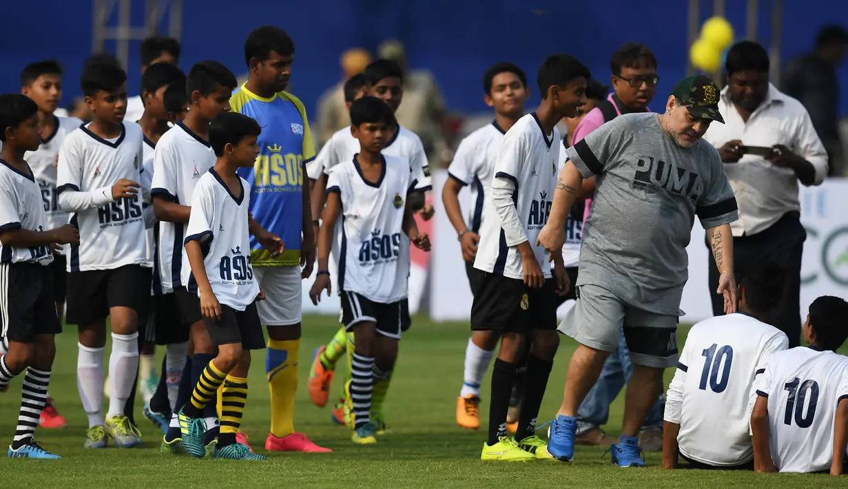 Legenda sepak bola, Diego Maradona, memberikan pelatihan kepada anak-anak di Barasat, Selasa (12/12/2017). Kunjungan ini dilakukan pria asal Argentina itu dalam rangkaian liburan. (AFP/Dibyangshu Sarkar)