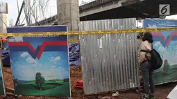 Seorang wanita mengambil gambar tiang girder Tol Bekasi-Cawang-Kampung Melayu (Becakayu) yang ambruk di Kebon Nanas, Jakarta Timur, Selasa (20/2). Peristiwa terjadi saat para pekerja melakukan pengecoran pada penyangga tiang. (Liputan6.com/Arya Manggala)