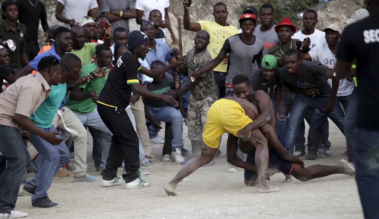 Para pria Haiti sedang beradu ketahanan pada ajang Gulat yang disebut Pinge wrestling competition di Port-au-Prince, Haiti, Sabtu (26/3/2016). Acara ini untuk memperingati Paskah di Haiti. (REUTERS/Andres Martinez Casares)