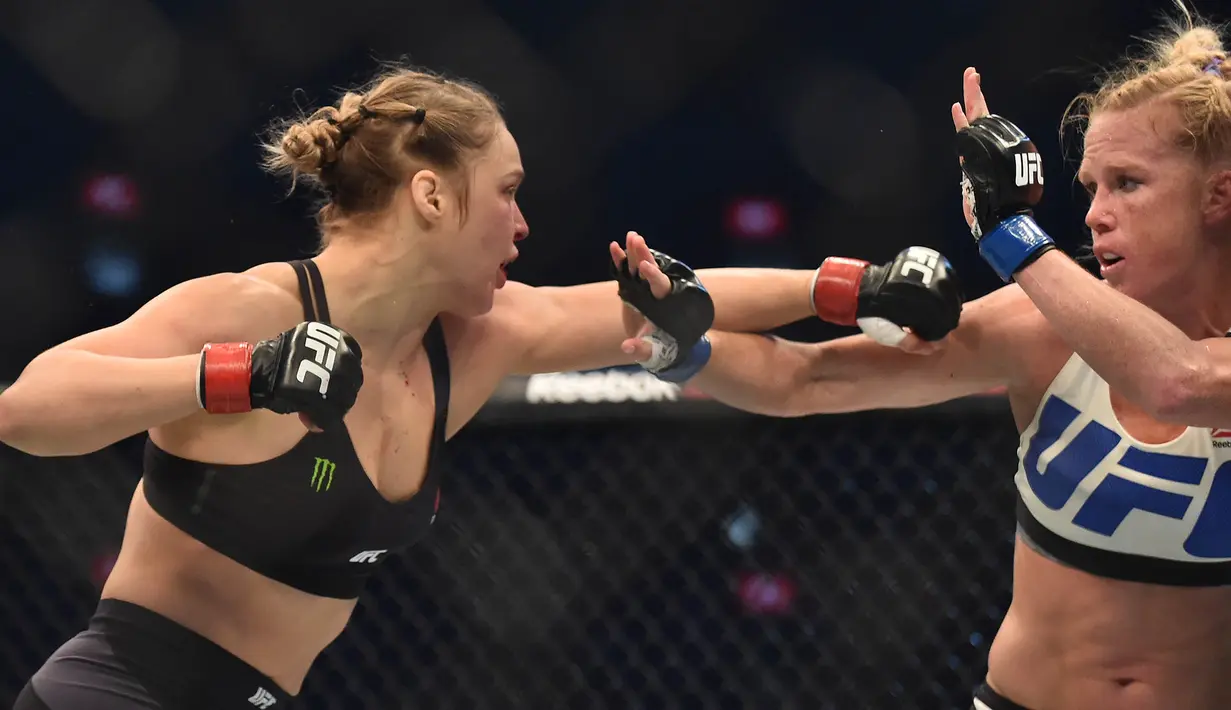 Ronda Rousey, berusaha memukul Holly Holm, pada pertarungan perebutan gelar juara kelas bantam UFC Women di Stadion Etihad, Melbourne, Minggu (15/11/2015). (AFP Photo/Paul Crock)