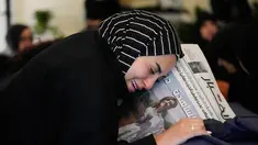 Zainab, saudara perempuan jurnalis Lebanon Amal Khalil yang tewas dalam serangan udara Israel pada Rabu 22 April 2026, memegang koran yang menampilkan potret saudara perempuannya, saat ia berduka di atas peti matinya di desa Baysariyeh, Lebanon Selatan, Kamis 23 April 2026. Jurnalis surat kabar Al-Akhbar, Amal Khalil, ditemukan meninggal dunia imbas serangan udara Israel di Kota al-Tayri, Lebanon Selatan pada Rabu 22 April 2026. (AP Photo/Mohammed Zaatari)