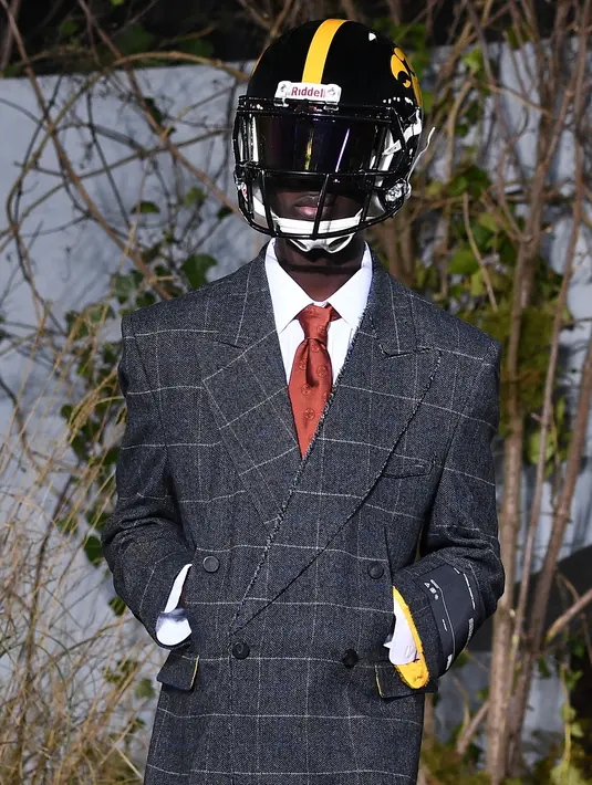 Seorang model mengenakan rancangan koleksi Fall/Winter 2019 dari brand Off-White pada Paris Fashion Week, Rabu (16/1). Dalam perhelatan itu, sejumlah model mengenakan helm futbol, saat melenggang di catwalk. (Anne-Christine POUJOULAT / AFP)