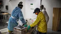 Para pengurus memindahkan jenazah pasien virus corona COVID-19 ke dalam peti mati di rumah duka AVBOB, Soweto, Afrika Selatan, 24 Juli 2020. (MARCO LONGARI/AFP)