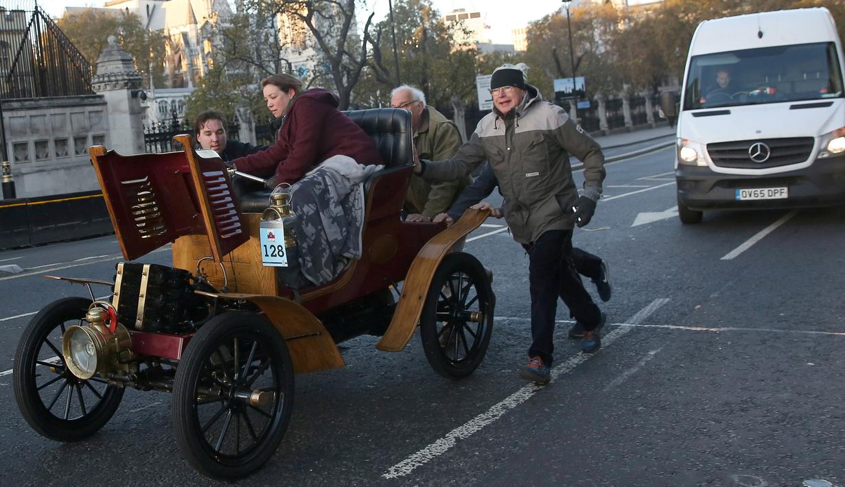 Peserta mendorong mobil antik mereka yang mogok saat mengikuti kegiatan tur tahunan dengan mobil veteran dari London ke Brighton di London, Inggris (6/11). Mobil-mobil tersebut ada yang usianya sudah lebih dari 100 tahun. (Reuters/Neil Balai)