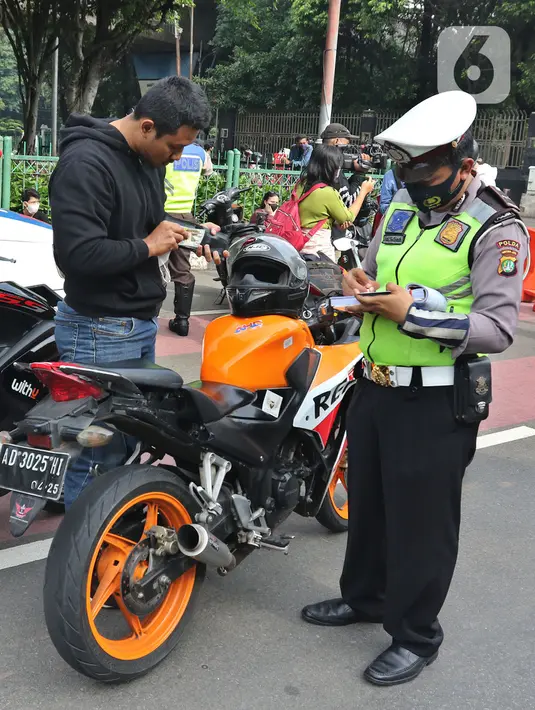 Petugas Kepolisian melakukan razia pengendara motor dengan knalpot bising di kawasan Monumen Nasional (Monas), Jakarta, Minggu (7/3/2021). Razia knalpot bising tersebut guna memberikan kenyamanan bagi warga yang hendak berolahraga di area tersebut. (Liputan6.com/Herman Zakharia)
