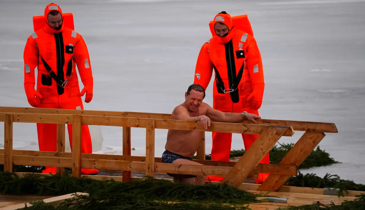 Petugas penyelamat mengamati seorang penganut Ortodoks Rusia yang berendam dalam air es saat perayaan tradisional Epiphany di Kronstadt, luar St. Petersburg, Rusia,  18 Januari 2023. Ribuan pengikut Gereja Ortodoks Rusia terjun ke sungai dan kolam es di seluruh negeri untuk menandai Epiphany, membersihkan diri dengan air yang dianggap suci untuk hari itu. (AP Photo/Dmitri Lovetsky)