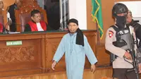 Terdakwa terorisme, Aman Abdurrahman menuju kursi pesakitan pada sidang pembacaan vonis di PN Jakarta Selatan, Jumat (22/6). Sesuai kesepakatan dengan KPI, persidangan tidak boleh disiarkan secara langsung di stasiun TV. (Liputan6.com/Angga Yuniar)