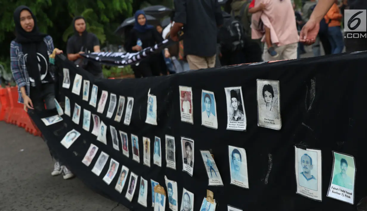 Aktivis bersiap menggulung deretan foto korban saat aksi Kamisan ke-562 di depan Istana Merdeka, Jakarta, Kamis (15/11). Mereka meminta pemerintah menyelesaikan kasus pelanggaran HAM berat khususnya Tragedi Semanggi 1. (Liputan6.com/Helmi Fithriansyah)