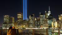 Sepasang kekasih menikmati ‘Tribute in Light’ dari sisi Brooklyn Promenade untuk mengenang tragedi serangan WTC di New York, Minggu (10/9). Kota New York memperingati 16 tahun tragedi serangan bom pada 11 September 2001 silam. (AP Photo/Mark Lennihan)