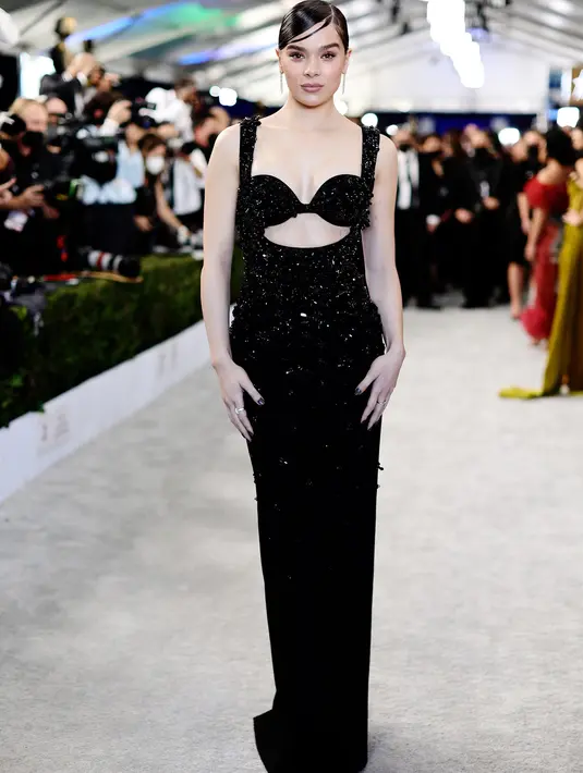 Hailee Steinfeld tampil dalam balutan gaun hitam berkilau dari Miu Miu dengan streamlined floor-length column skirt, back slit, dan tali bahu yang lebar. Penampilannya di red carpet SAG Awards ini dilengkapi dengan cincin berlian Tiffany & Co. dan anting berbentuk daun.