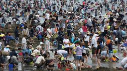 Sejumlah pengunjung menggali pasir untuk berburu kerang di pantai kawasan Yokohama, dekat Tokyo, Senin (30/4). Puluhan ribu orang berdesakan di pantai selama Golden Week atau periode liburan di Jepang pada akhir April hingga awal Mei. (AP/Koji Sasahara)