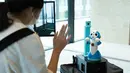 Seorang pengunjung berinteraksi dengan robot dalam uji coba yang dilakukan di sebuah bangunan komersial di Tokyo, Jepang (14/9/2020). Ajang ini untuk menguji coba cara kerja robot dalam memandu, memeriksa suhu, telepresensi, dan sejumlah fungsi lainnya. (Xinhua/Pemerintah Kota Metropolitan Tokyo)