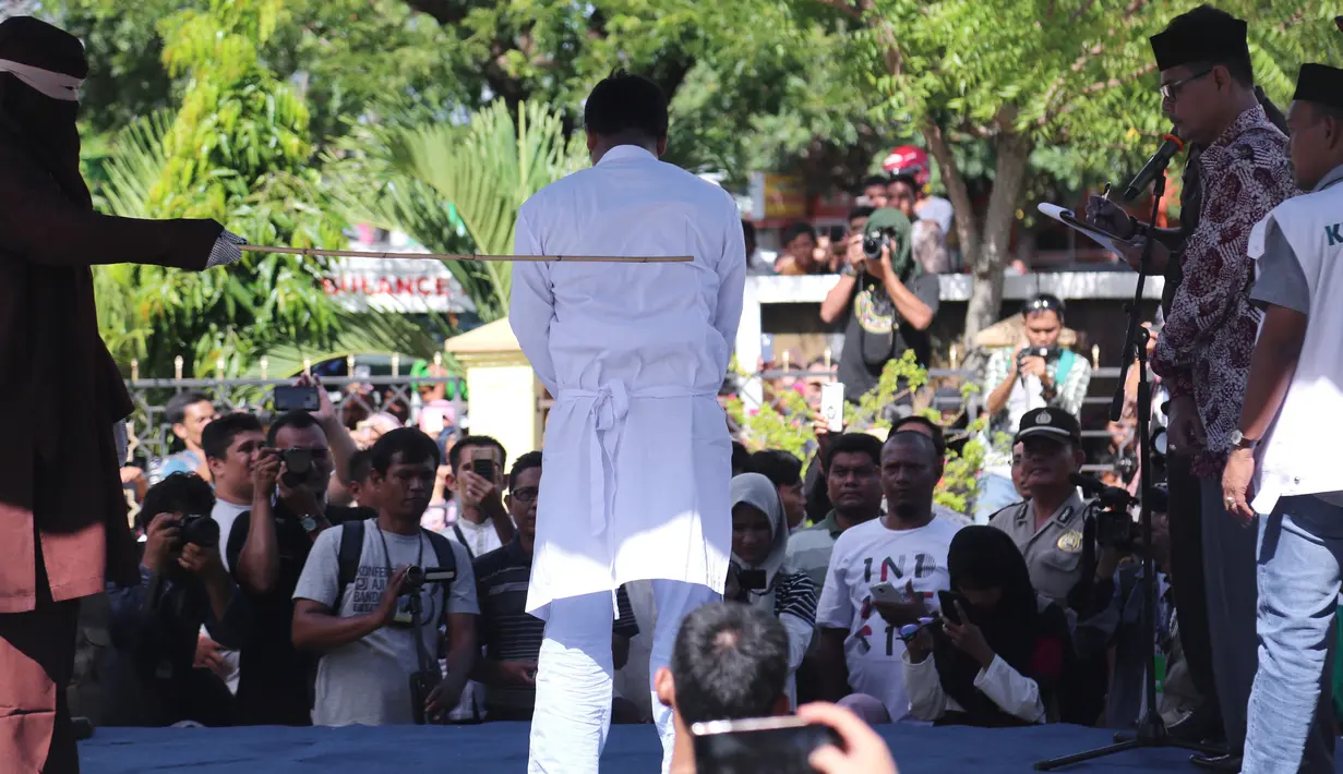 Salah satu dari dua pria terpidana kasus liwath alias gay saat dicambuk di depan Masjid Baiturrahim, Banda Aceh, (13/7). Mahkamah Syariah Kota Banda Aceh menjatuhi hukuman cambuk pasangan gay Nyakrab Bumin dan Muhammad Rustam. (AP Photo/Heri Juanda)