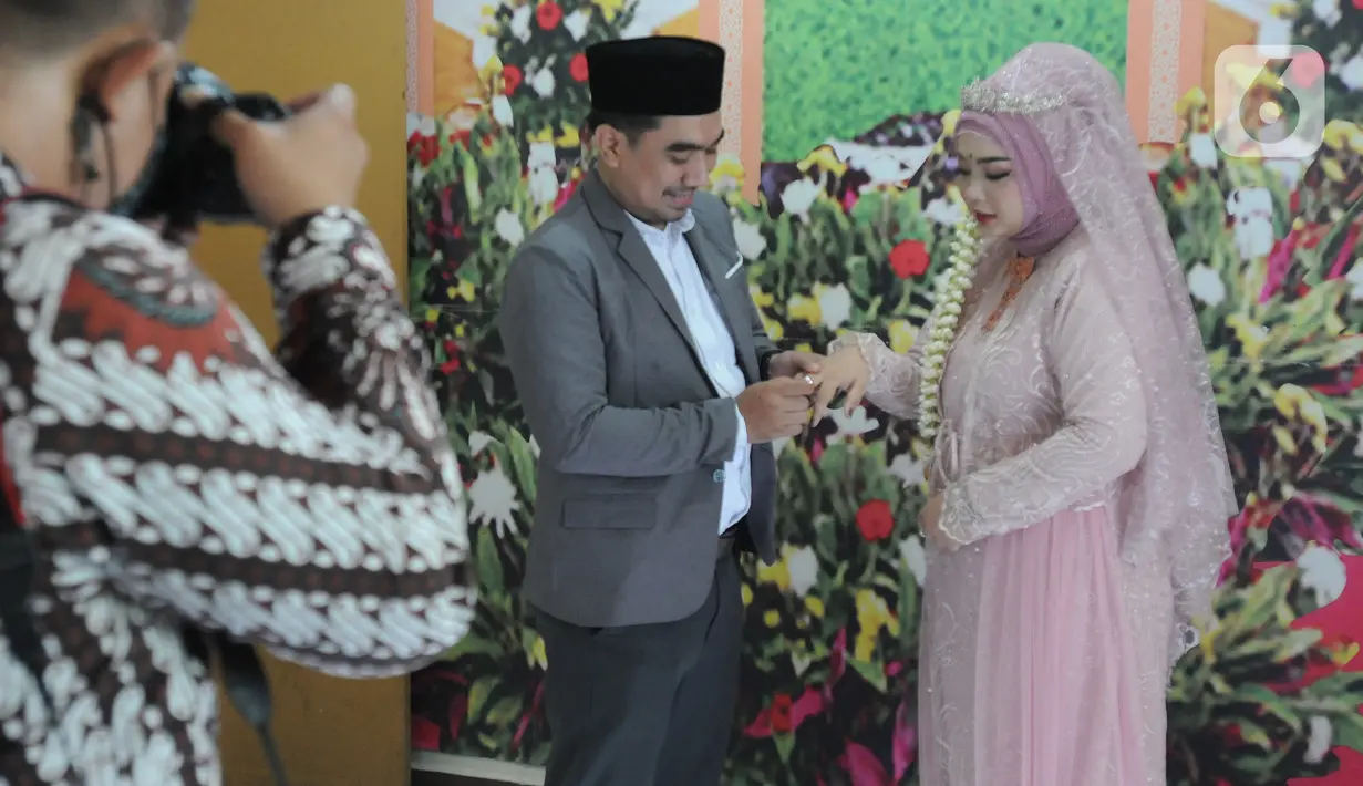 Suasana prosesi pernikahan sepasang pengantin di KUA Pamulang, Tangerang Selatan, Selasa (22/2/2022). Sebanyak 10 pasangan menjalankan akad nikah di KUA Pamulang pada hari ini yang dianggap memiliki tanggal cantik. (merdeka.com/Arie Basuki)
