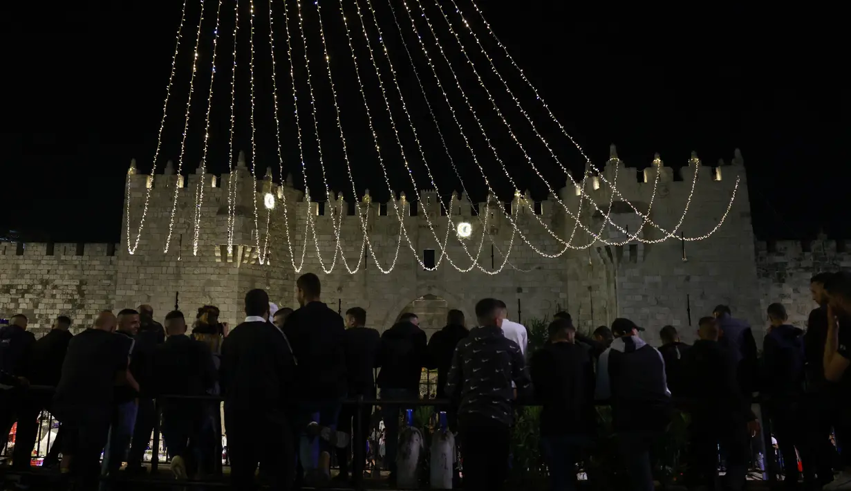 Warga Palestina berkumpul pada hari pertama bulan suci Ramadhan di luar gerbang Damaskus di Kota Tua Yerusalem, 2 April 2022. Ramadan adalah bulan suci umat Islam yang dirayakan dengan cara melaksanakan puasa selama satu bulan penuh. (Menahem KAHANA / AFP)