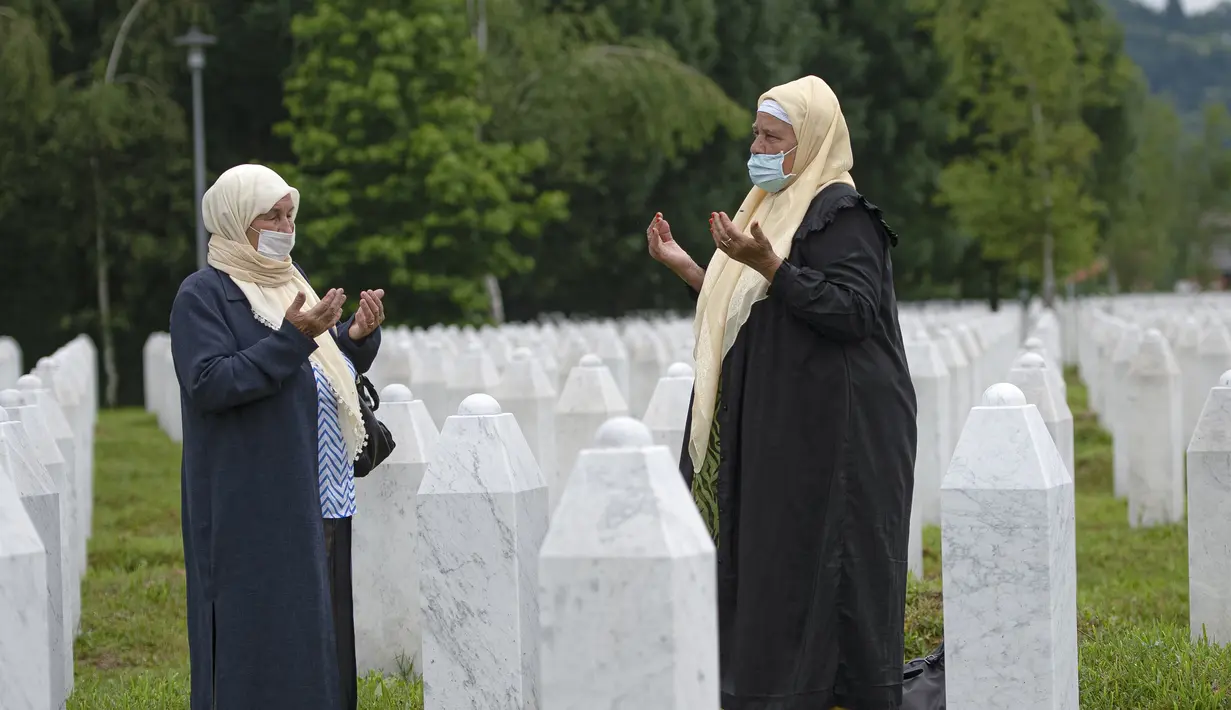 Dua wanita berdoa di pemakaman korban pembantaian Sreberenica, Potocari, Bosnia, 7 Juli 2020. Lebih dari 8.000 muslim Bosnia tewas dalam 10 hari pembantaian setelah kota itu dikuasai pasukan Serbia pada bulan-bulan terakhir perang saudara 1992-1995. (AP Photo/Kemal Softic)