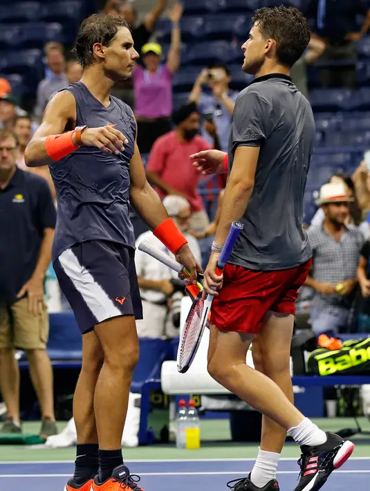 Petenis Spanyol, Rafael Nadal dan Dominic Thiem dari Austria usai pertandingan perempat final turnamen AS Terbuka 2018 di New York, AS, (5/9). Nadal menang lewat pertarungan maraton lima set 0-6, 6-4, 7-5, 6-7 (4-7), 7-6 (7-5). (AP Photo/Adam Hunger)