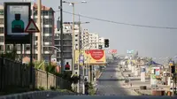 Warga Palestina berjalan di jalan sepi di tepi pantai pada awal pemberlakukan lockdown total selama 48 jam di Kota Gaza, Selasa (25/8/2020). Lockdown dan jam malam diberlakukan di wilayah jalur Gaza menyusul terkonfirmasinya kasus Covid-19 pertamanya di sebuah kamp pengungsian. (MOHAMMED ABED/AFP)