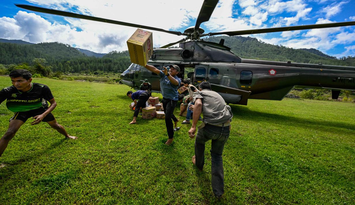 Warga membawa bantuan yang didistribusikan oleh personel TNI AU di wilayah terdampak banjir di Kabupaten Bener Meriah, Provinsi Aceh, pada Kamis 4 Desember 2025. Pendistribusian bantuan logistik bagi masyarakat terdampak banjir bandang di beberapa kabupaten di Aceh, terus dilakukan. (CHAIDEER MAHYUDDIN/AFP)