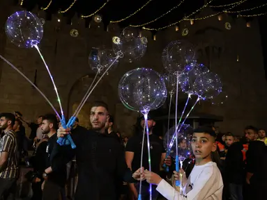 Warga Palestina menjual balon pada hari pertama bulan suci Ramadhan di luar gerbang Damaskus di Kota Tua Yerusalem, 2 April 2022. Ramadan adalah bulan suci umat Islam yang dirayakan dengan cara melaksanakan puasa selama satu bulan penuh. (Menahem KAHANA / AFP)