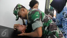 Seorang anggota TNI menenangkan anaknya yang diberi vaksin di Kantor Kesehatan Kopassus, Jakarta, Senin (18/7). Kopassus menggelar pelaksanaan vaksinasi ulang terhadap anak prajurit yang terindikasi menjadi korban vaksin palsu. (Liputan6.com/Helmi Afandi)