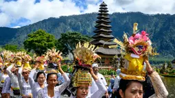 Daya tarik utama terletak pada dua pura yang paling menonjol, yakni Pelinggih Teling Segara dengan meru bertumpang 11 dan Pelinggih Linggah Ulun Danu dengan meru bertumpang tiga, yang terlihat mengambang di danau. Tampak dalam foto, umat Hindu bersiap mengikuti prosesi keagamaan di Pura Ulun Danu Beratan, sebuah pura Hindu di Danau Beratan dekat Bedugul, Bali, pada Jumat 7 November 2025. (Mladen ANTONOV/AFP)